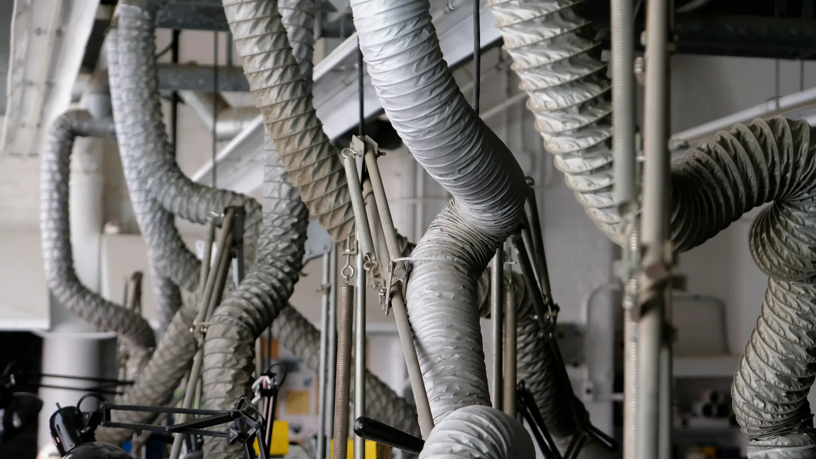 Mangueras flexibles de extracción suspendidas del techo en un taller industrial