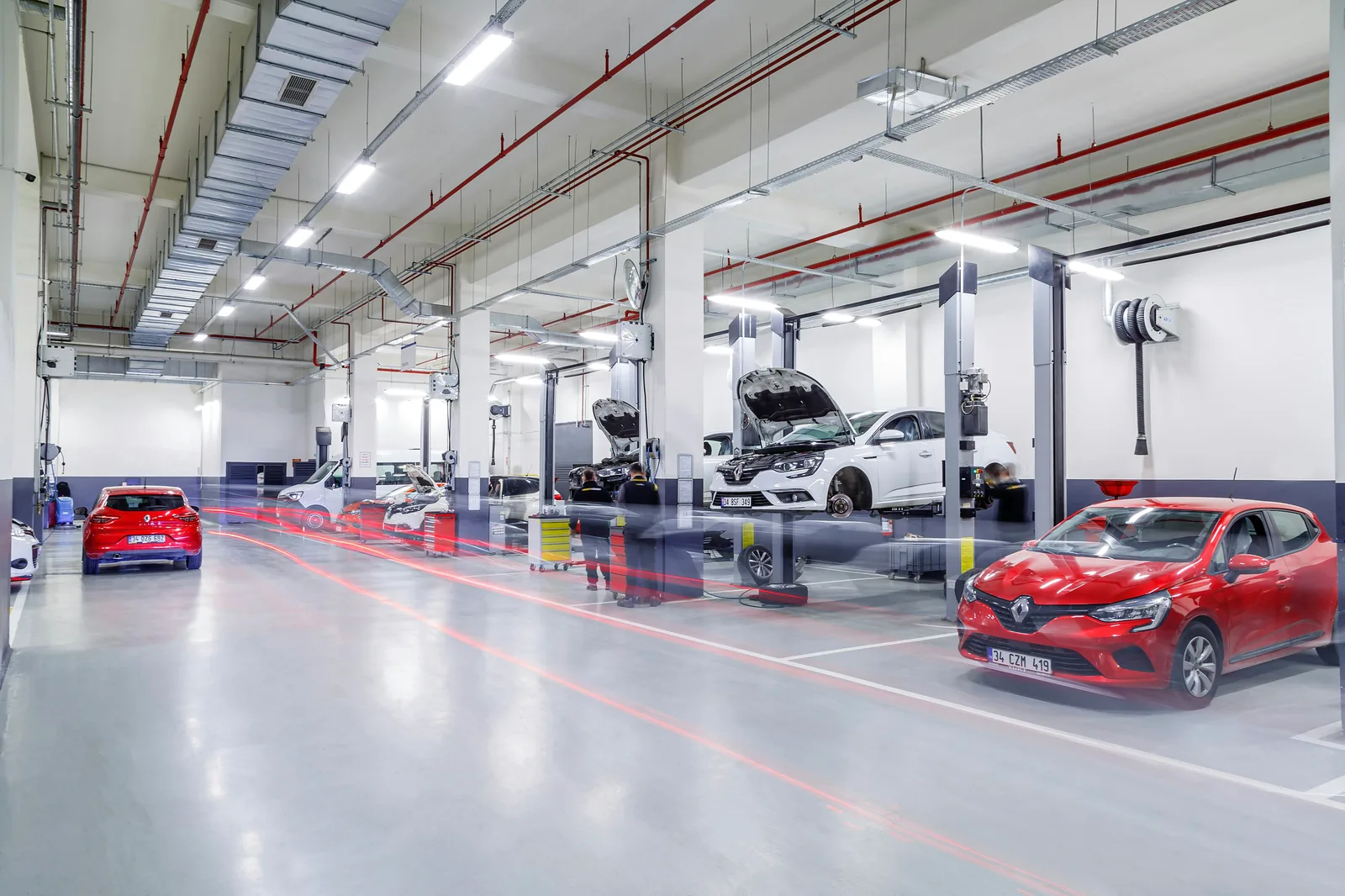 Taller automotriz amplio con elevadores, carretes de extracción en el techo y vehículos en las bahías