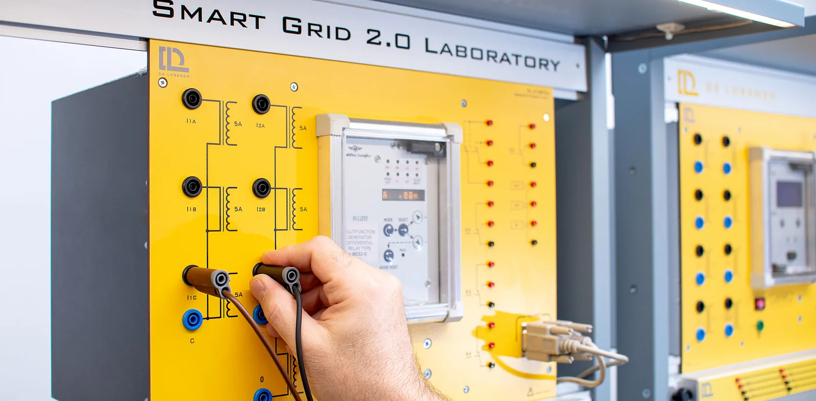 Mano conectando puntas de prueba en un módulo de un laboratorio de red eléctrica inteligente