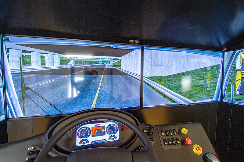 Vista de manejo desde la cabina de un simulador de bus con pantallas envolventes