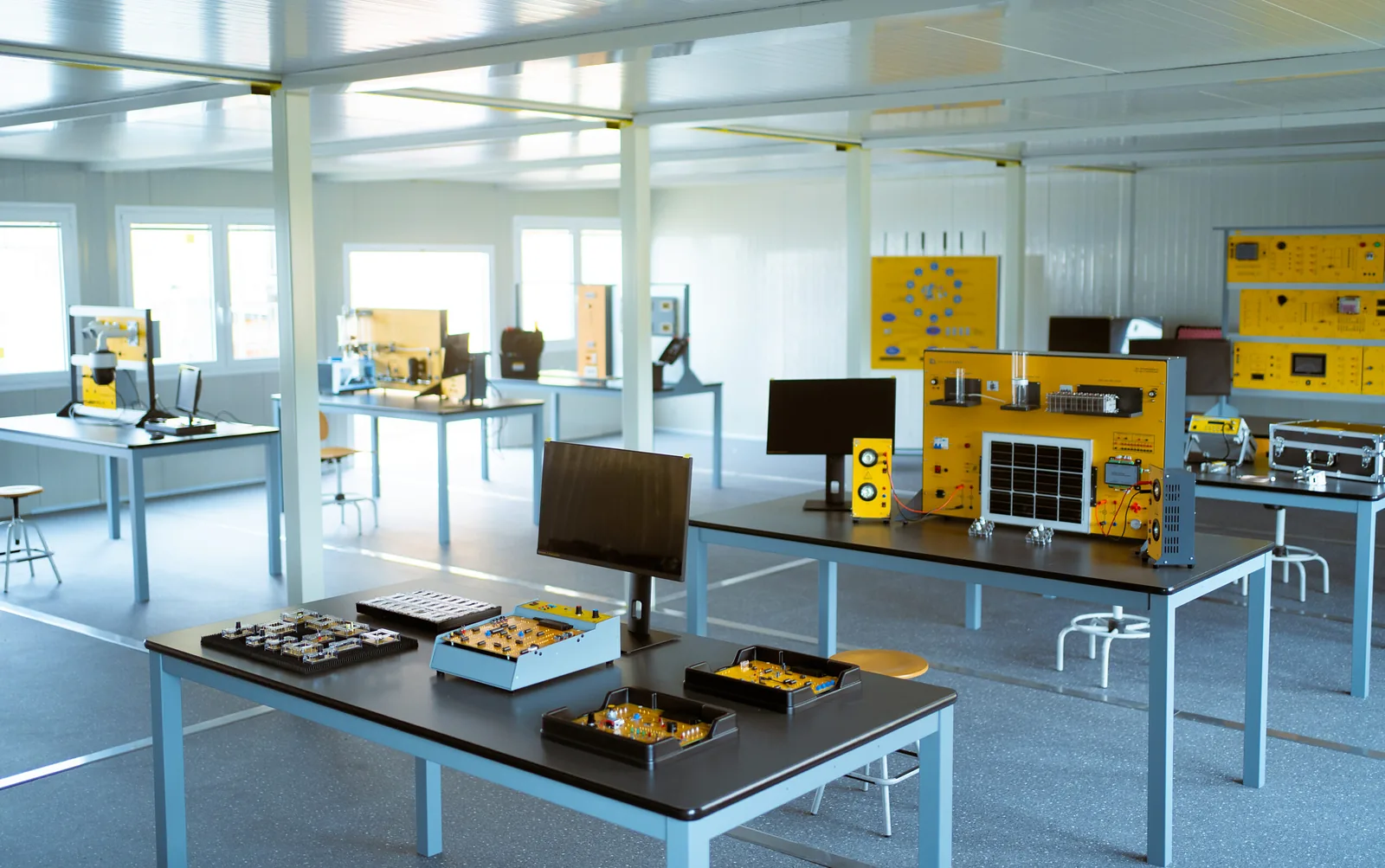 Laboratorio de formación técnica amplio y vacío, con mesas de trabajo, paneles entrenadores y monitores